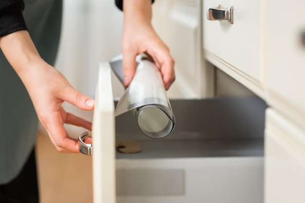 Plan rapproché des mains prenant le tapis de cuisson en silicone hors du tiroir de la cuisine