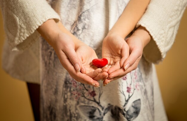 Plan rapproché de mère et de petite fille tenant le coeur rouge dans des mains