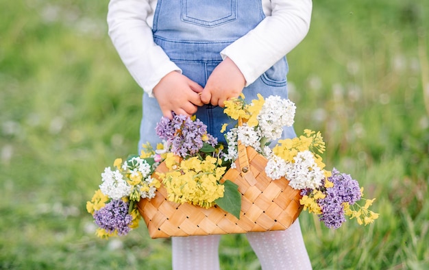 Plan rapproché d'un panier avec des fleurs dans les mains d'une fille