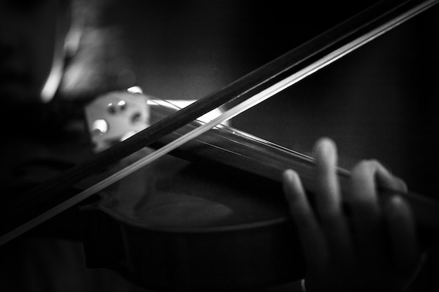 Plan rapproché, petite fille jouant du violon avec un orchestre instrumental, avec ton sombre et effet lumineux sombre et traité, sélectionné, mise au point avec une faible profondeur de champ