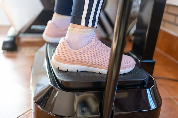 Plan rapproché des pieds des femmes sur une machine vibrante de gymnastique pour des sports à la maison