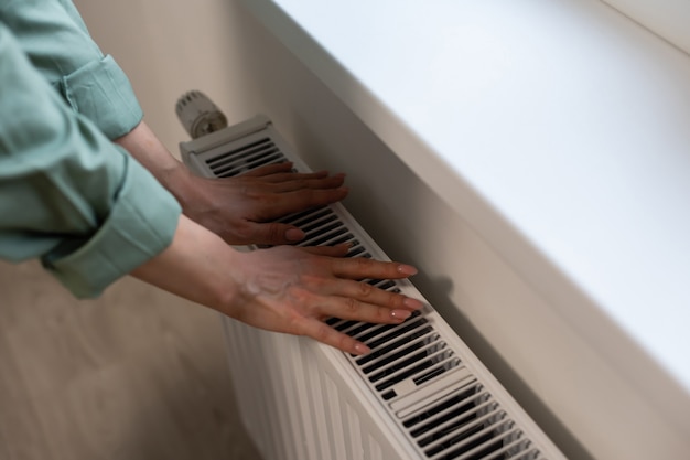 Plan rapproché d'un thermostat de radiateur avec la main de femme