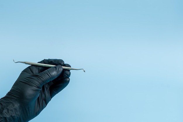 Plan recadré de dentiste professionnel dans des gants médicaux noirs avec outil dentaire Concept dentaire isolé sur fond bleu