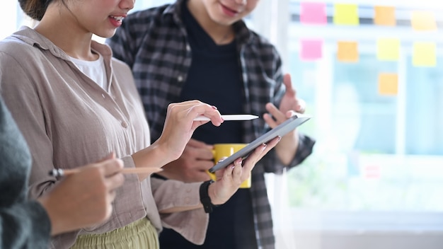 Plan recadré d'une équipe de créateurs utilisant une tablette numérique et ayant une réunion au bureau de création.