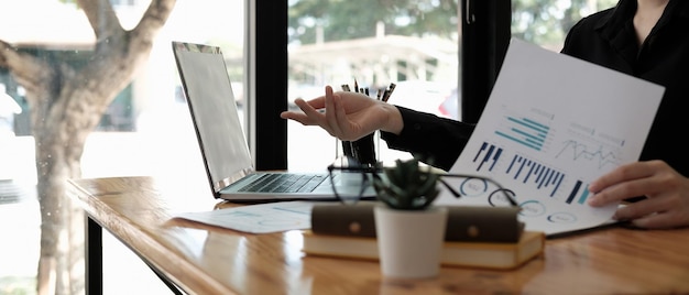 Plan recadré d'une femme d'affaires asiatique travaillant pour des documents de tableau de données de paperasse avec un concept financier d'entreprise d'ordinateur portable