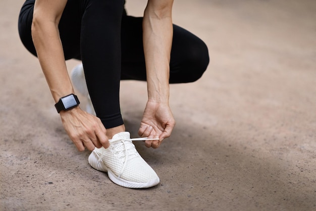 Plan recadré d'une femme attachant des lacets avant de courir à l'extérieur