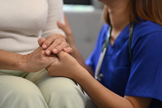 Plan recadré d'une infirmière attentionnée tenant les mains d'une femme âgée pour espérer et soutenir le concept de soins de santé pour personnes âgées