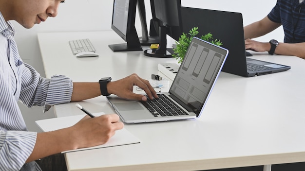 Plan recadré d'une jeune équipe de programmeurs pendant qu'ils travaillent / se concentrent sur le travail au bureau.