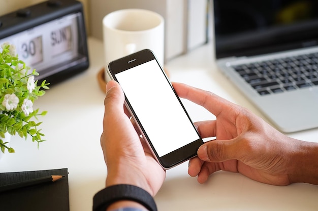 Plan recadré d'un jeune homme utilisant un téléphone intelligent avec écran blanc assis dans un bureau modernex9