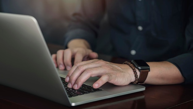 Plan recadré de la main de l'homme travaillant sur un ordinateur portable