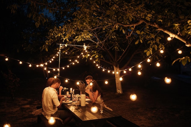 Plan recadré de quatre beaux amis en train de dîner dans l'arrière-cour