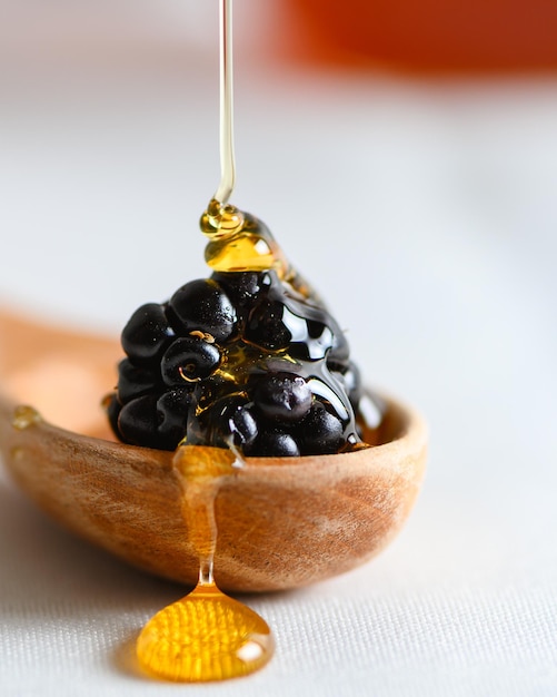 Plan vertical de délicieux caviar noir dans une cuillère en bois avec du miel dégoulinant dessus