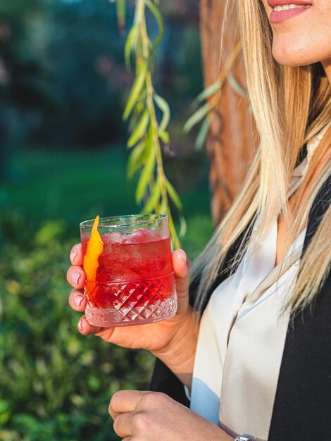 Plan vertical d'une femme blonde buvant un cocktail glacé