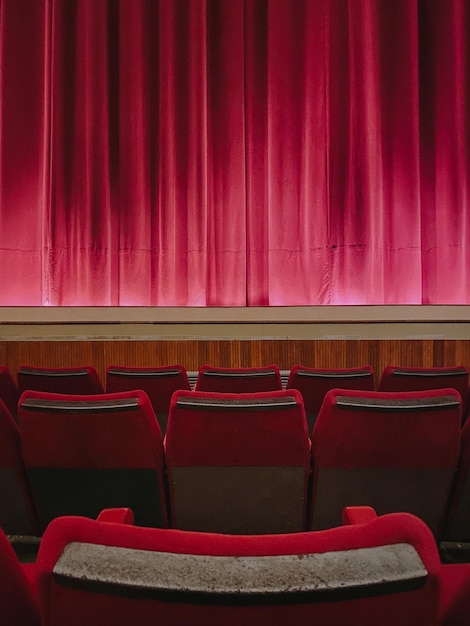 Photo plan vertical de sièges de théâtre vides rouges devant la scène