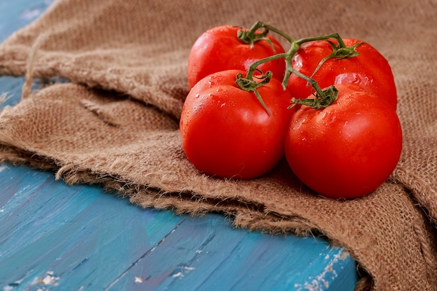 Planche de bois bleu photo horizontale de la branche de tomates juteuses rouge.