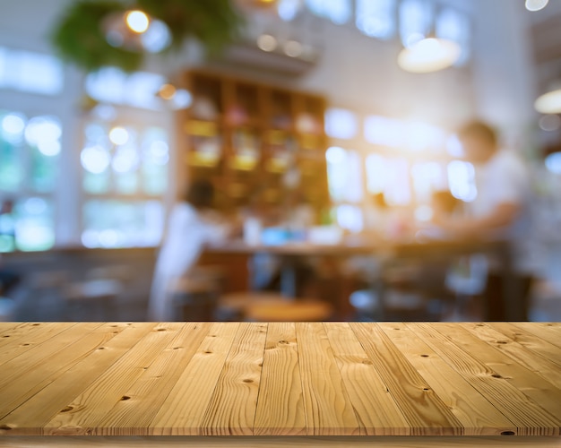 Planche de bois brun vieille planche vide comme maquette étagère ou table avec groupe flou de client dans un café ou un bistro et bokeh doux à partir d'une lampe électrique et d'un éclairage de fenêtre