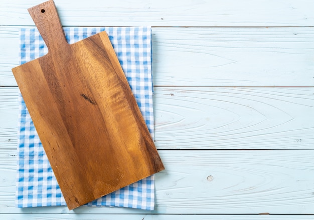 Planche de bois coupe vide avec un torchon de cuisine sur fond en bois, vue de dessus