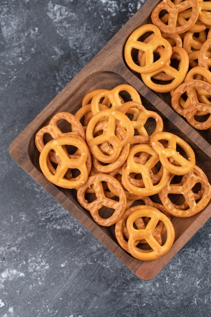 Une planche de bois de craquelins bretzels secs salés placés sur une surface en pierre