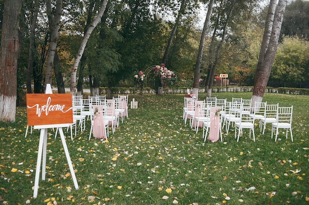 Planche de bois avec l'inscription Bienvenue. Cérémonie de mariage prête avec des chaises et un décor