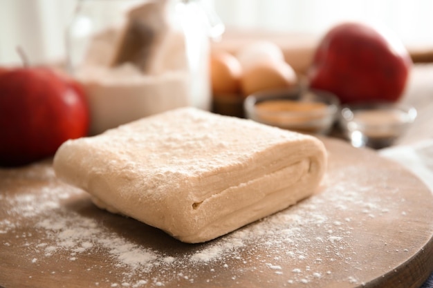 Planche de bois avec pâte feuilletée crue sur table