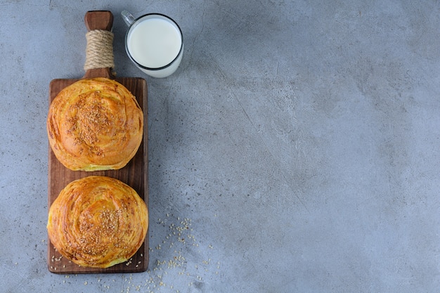 Une planche en bois de pâtisserie nationale azerbaïdjanaise avec une tasse en verre de lait frais