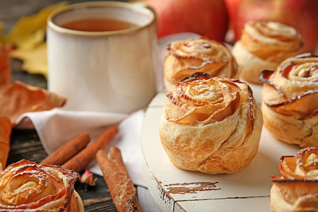 Planche de bois avec des roses de pomme de pâte feuilletée sur le gros plan de table