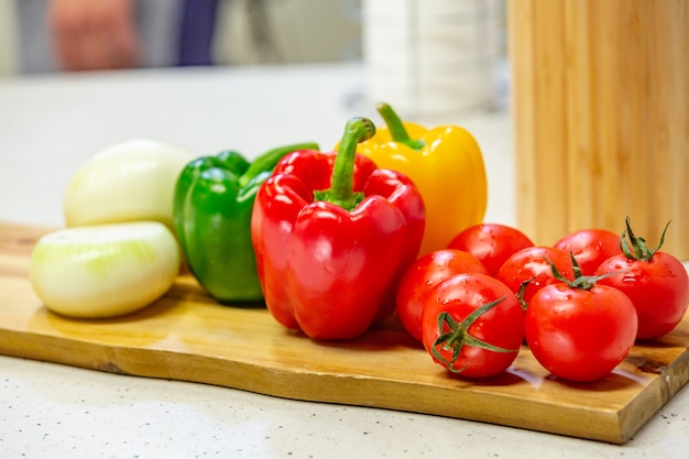 Sur une planche de bois sont des légumes. Tomate, poivron, salade appétissante s'allonger sur une planche de bois