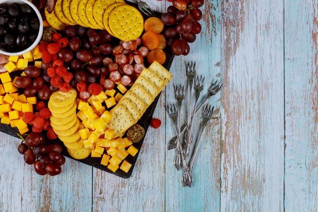 Planche de charcuterie avec fromage, raisin, framboise et craquelins