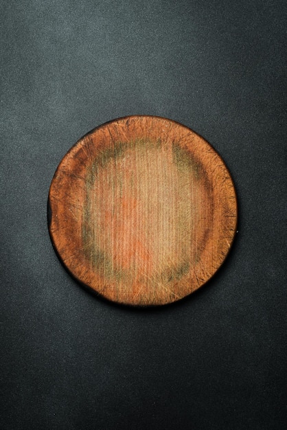 Planche de coupe ronde de cuisine Planche brune ustensiles de cuisine sur un fond sombre