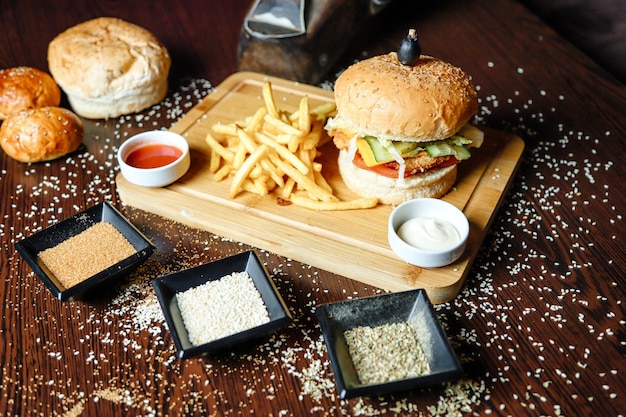 Une planche à couper en bois avec des hamburgers et des frites.