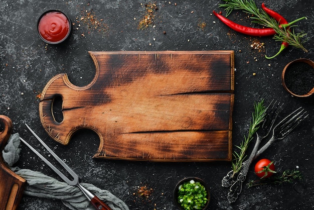 Planche de cuisine et légumes aux épices sur fond de pierre noire Vue de dessus Espace libre pour votre texte