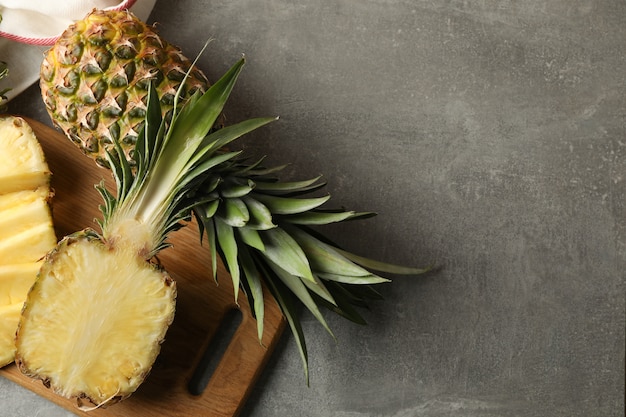 Planche à découper avec des ananas sur fond gris, vue de dessus