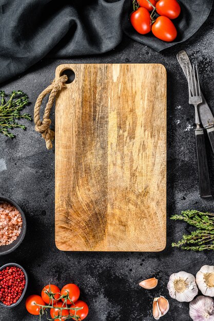 Planche à découper en bois entourée de légumes et d'épices