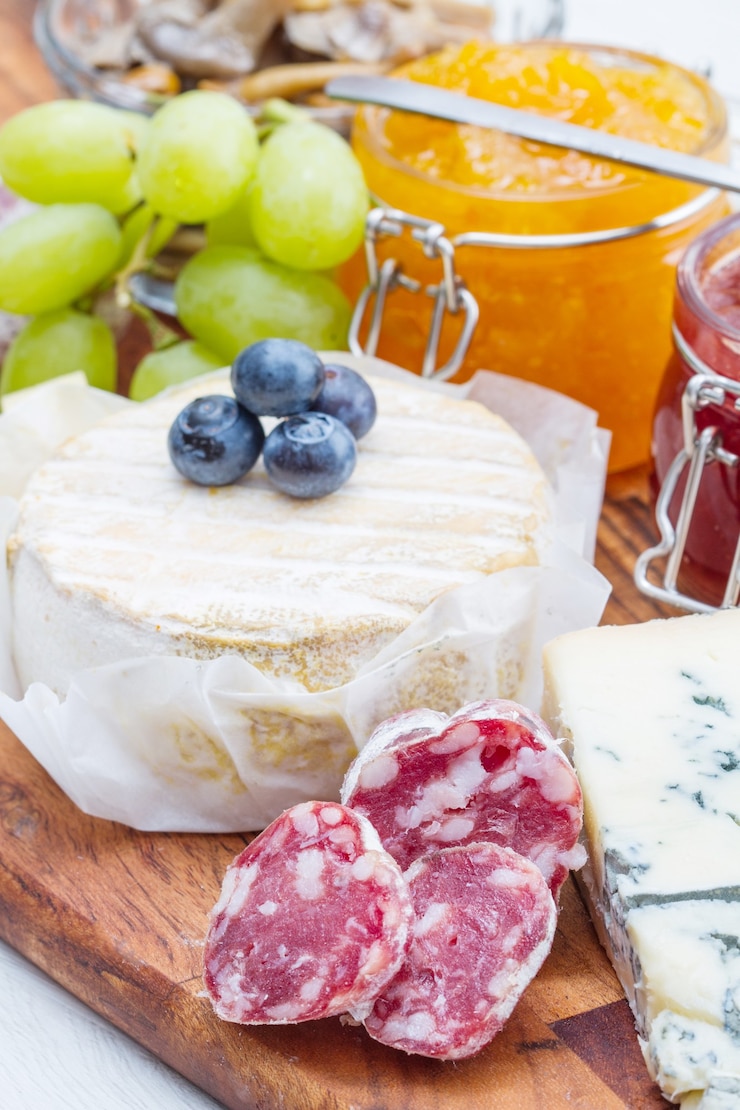 Photo planche à découper en bois avec fromage, charcuterie et confitures
