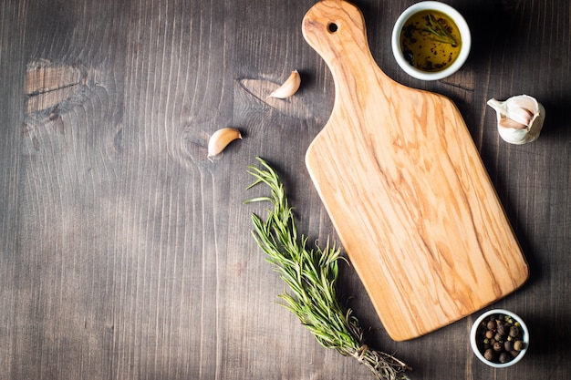 Photo planche à découper en bois avec des herbes fraîches et des légumes crus sur une table en bois rustique. vue de dessus. fond de cuisine.