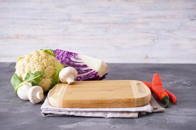 Planche à découper en bois et légumes sur table en bois, espace pour le texte.