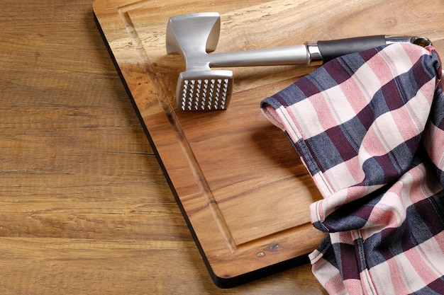 Photo planche à découper en bois et marteau à viande.