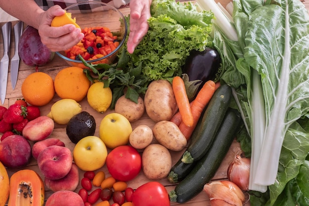 Planche à découper en bois pleine de fruits et légumes crus Une femme prépare une salade de fruits végétariens