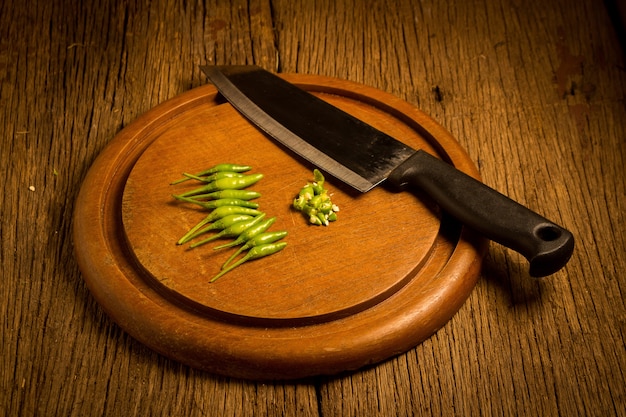 Planche à découper en bois rond. piments verts et rouges. couteau