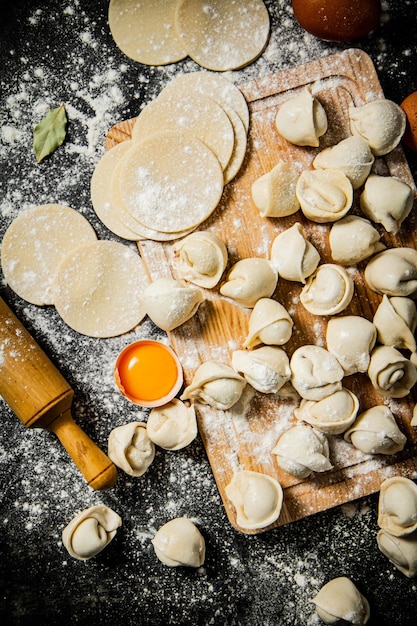 Une planche à découper en bois avec un tas de raviolis dessus.