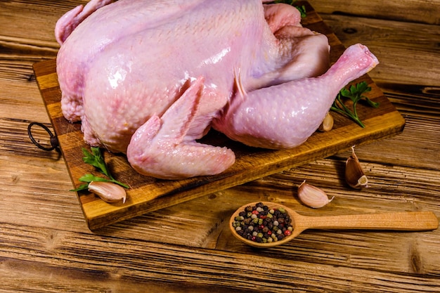 Planche à découper en bois avec tout l'ail et les épices de poulet non cuits