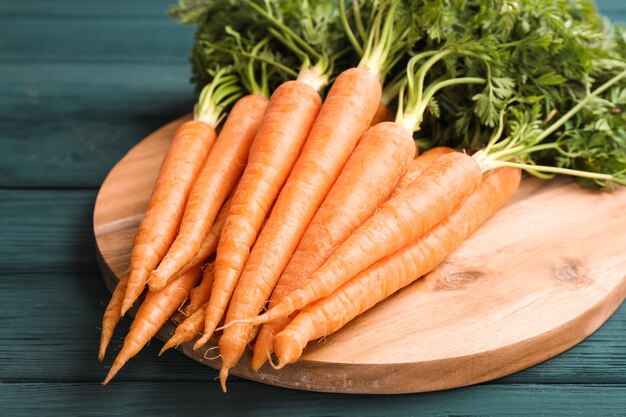 Planche à découper avec des carottes mûres sur table en bois