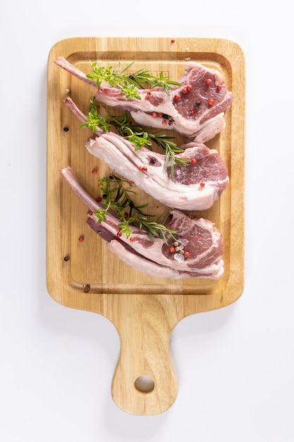 Planche à découper de côtes d'agneau cru aux épices et légumes rôtis