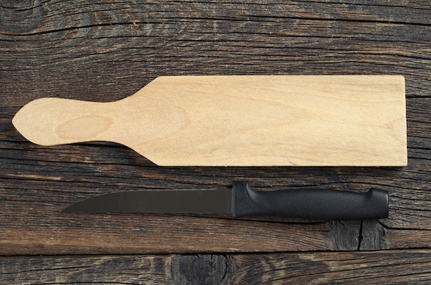 Planche à découper et couteau vides sur la vieille surface en bois, vue de dessus