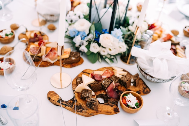 Une planche à découper avec des délices sur la table avec une nappe blanche et des bougies en chandeliers