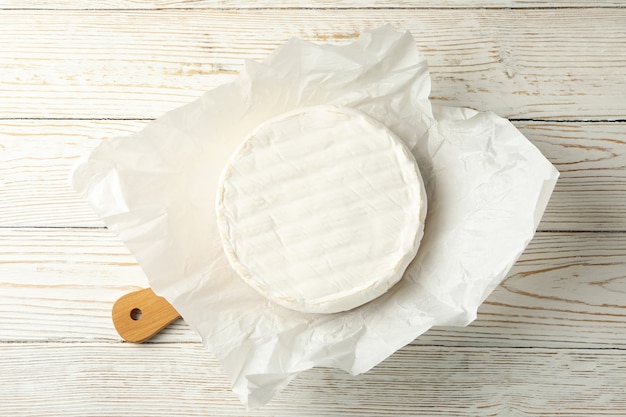 Planche à découper avec du fromage camembert sur fond de bois