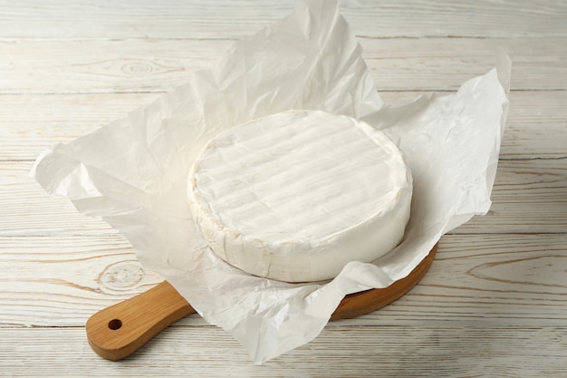 Planche à découper avec du fromage camembert sur fond de bois