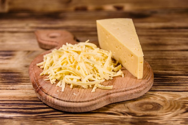 Planche à découper avec du fromage râpé sur une table en bois rustique