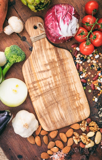 Planche à découper sur fond de bois Planche à découper en bois vide entourée de légumes et de noix