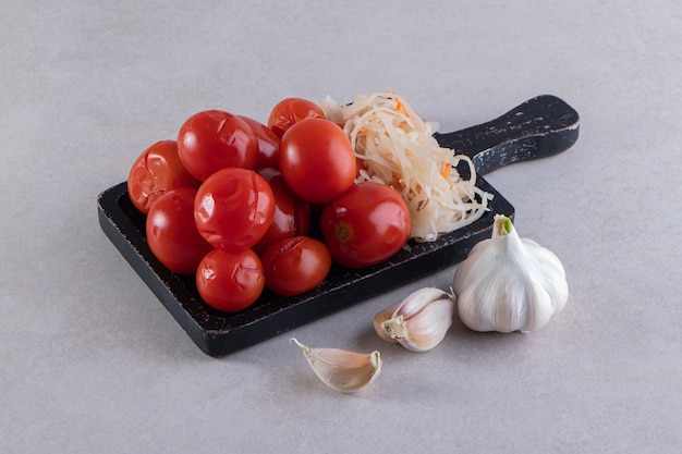 Planche à découper noire de tomates marinées et de chou sur pierre.